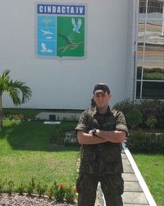 Walter Robôs jovem, de farda, diante do brasão do CINDACTA IV